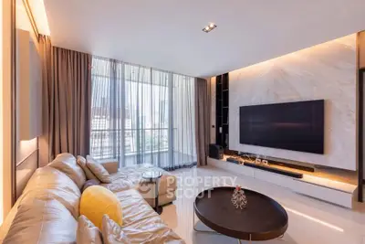 Luxurious modern living room with large TV and city view, featuring elegant decor and natural light.