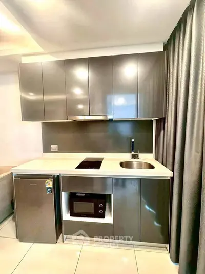 Modern compact kitchen with sleek cabinetry and built-in appliances in a stylish apartment.