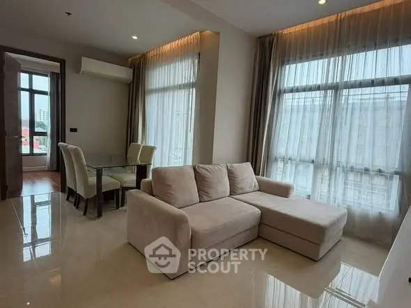Spacious living room with modern furniture and large windows in a high-rise apartment.
