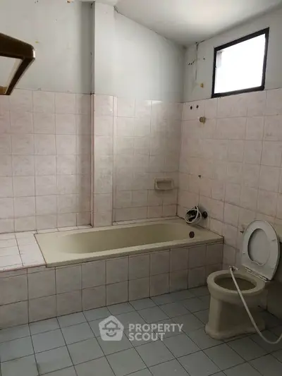 Spacious bathroom with bathtub and tiled walls, ideal for renovation.