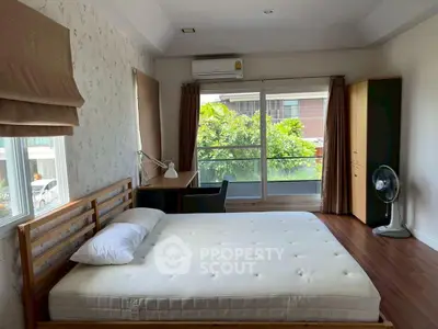 Spacious bedroom with large window and garden view, featuring a wooden bed and modern furnishings.