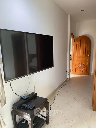 Modern living room with wall-mounted TV and elegant wooden door