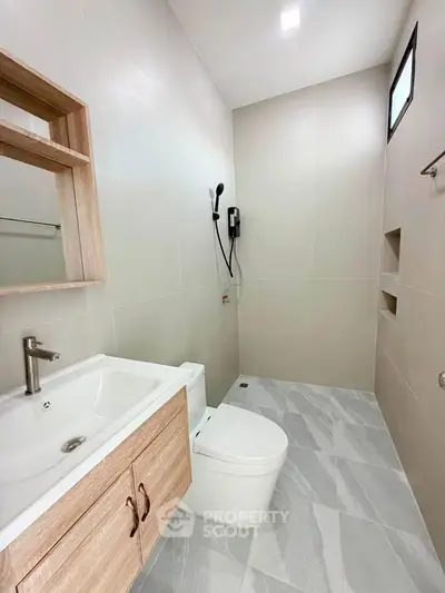 Modern bathroom with sleek fixtures and minimalist design, featuring a spacious shower area and elegant vanity.