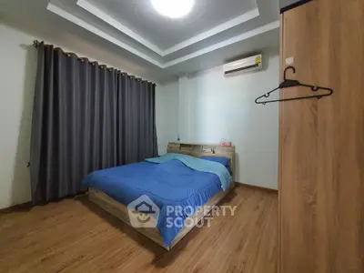 Cozy bedroom with modern design, featuring wooden flooring and stylish ceiling lights.