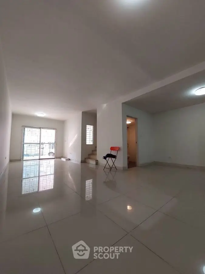 Spacious empty living room with glossy tiled floors and staircase