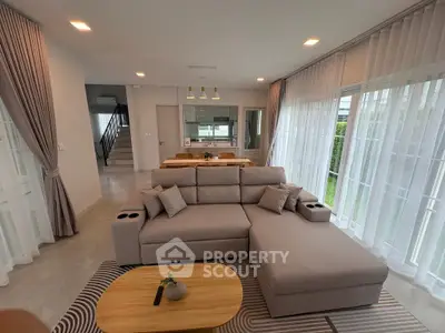 Spacious modern living room with elegant sofa and large windows offering natural light.
