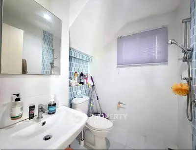 Modern bathroom with sleek fixtures and blue tile accents, featuring a shower and ample storage space.