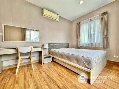 Spacious bedroom with polished wooden flooring, large windows with curtains, and modern furniture including a study desk.