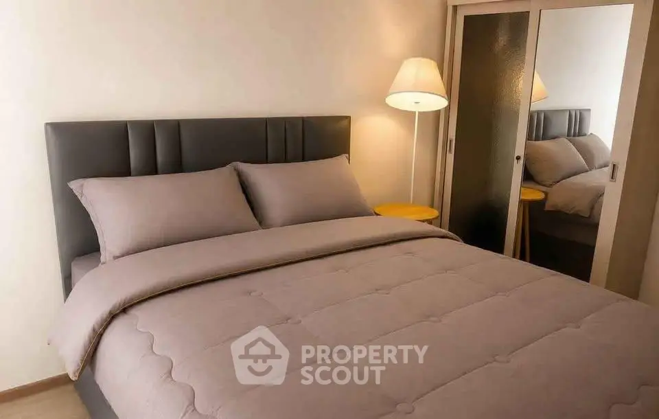 Cozy bedroom with modern decor and plush bedding, featuring a stylish headboard and mirrored closet doors.