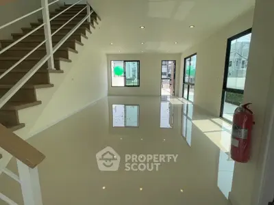 Spacious modern living room with staircase and large windows in a bright home