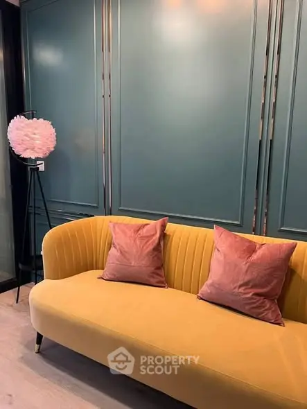 Stylish living room with yellow sofa and pink cushions against elegant teal panel wall.