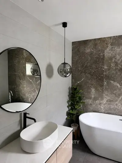 Modern bathroom with freestanding tub and stylish round mirror