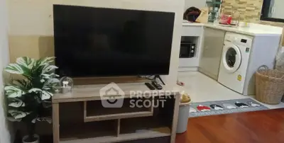 Cozy living room with modern TV setup and adjacent laundry area featuring washing machine.