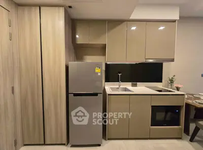 Modern kitchen with sleek cabinets, fridge, and built-in oven in stylish apartment.