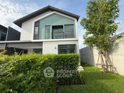 Modern two-story house with large windows and lush green garden