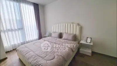 Spacious bedroom with elegant decor and large window for natural light.