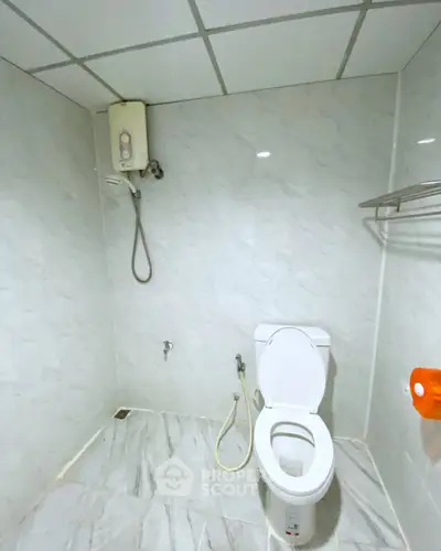 Modern bathroom with sleek white tiles and essential fixtures.