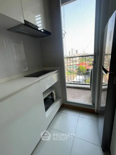 Modern kitchen with sleek white cabinetry and balcony view in urban apartment