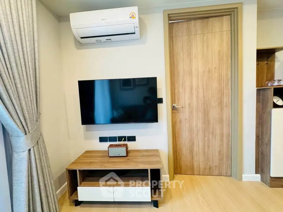 Modern living room with wall-mounted TV and air conditioning in stylish apartment.