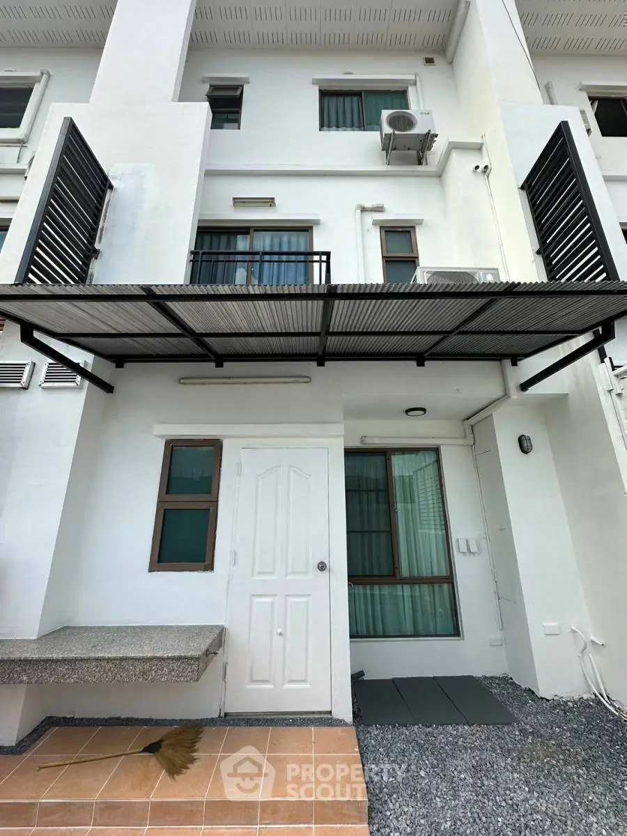 Modern townhouse exterior with balcony and air conditioning unit, showcasing sleek design and functional outdoor space.