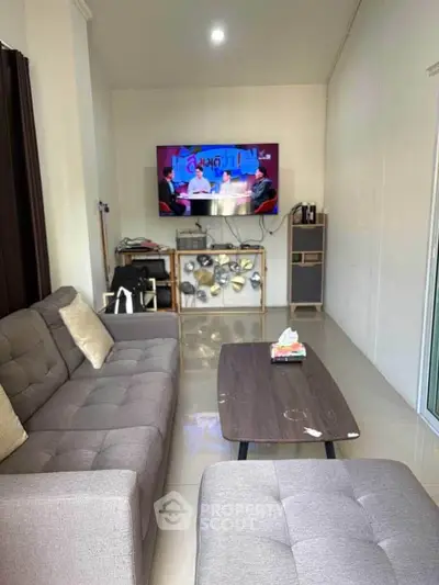 Cozy living room with modern gray sofa and wall-mounted TV, perfect for relaxation.