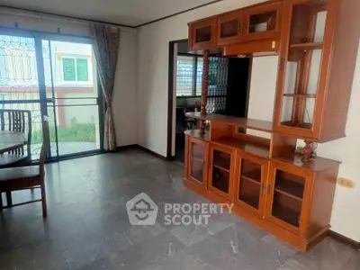 Spacious living room with wooden cabinet and sliding glass doors leading to balcony.