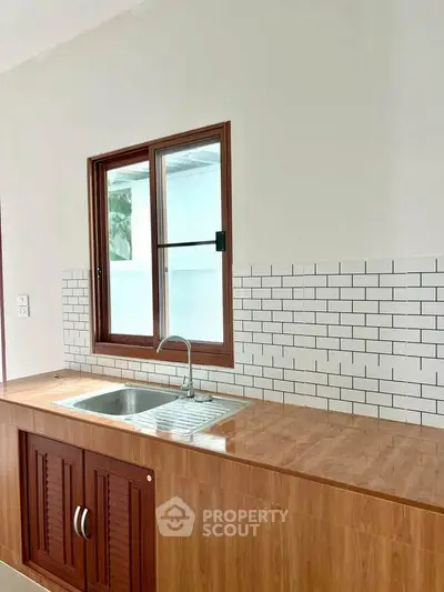 Modern kitchen with wooden cabinets and subway tile backsplash, featuring a sleek stainless steel sink.