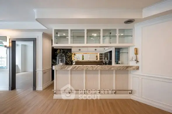 Elegant home bar with glass cabinets and marble countertop in spacious living area.