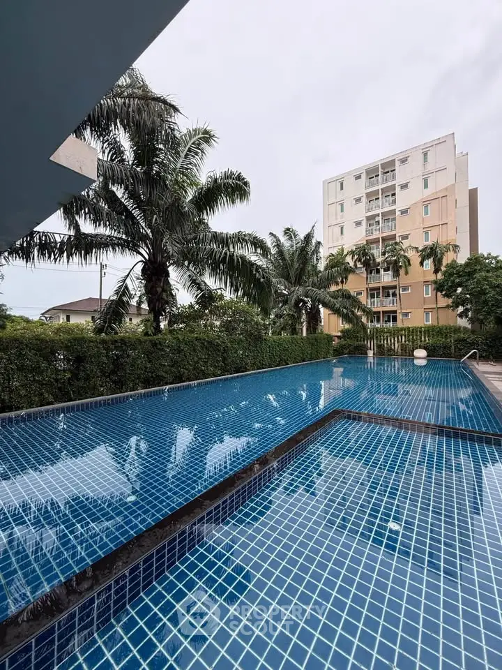 Luxurious outdoor pool with palm trees and modern building backdrop