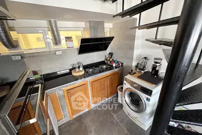 Modern kitchen with spiral staircase and washing machine, featuring sleek appliances and wooden cabinetry.
