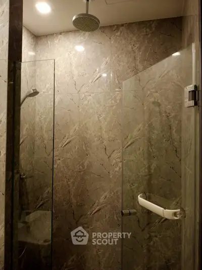 Luxurious marble-tiled bathroom with modern shower enclosure and sleek fixtures.