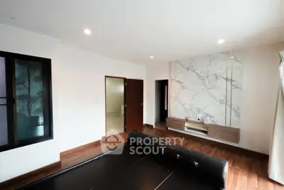 Spacious modern living room with elegant marble accent wall and wooden flooring.