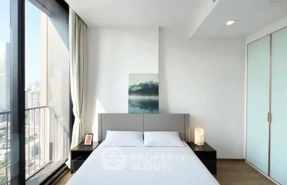 Modern bedroom with large windows and city view, featuring minimalist decor and natural light.