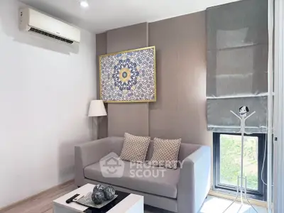 Modern living room with stylish decor, featuring a cozy sofa, elegant wall art, and natural light from a large window.