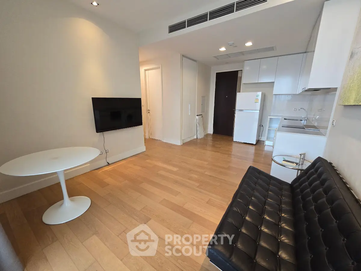 Modern living room with sleek furniture and open kitchen layout in a stylish apartment.