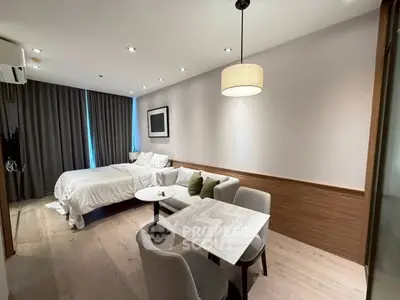 Modern studio apartment with cozy bed, stylish dining area, and elegant lighting.