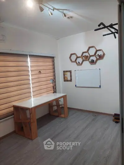 Modern study room with wooden desk, hexagonal shelves, and window blinds.