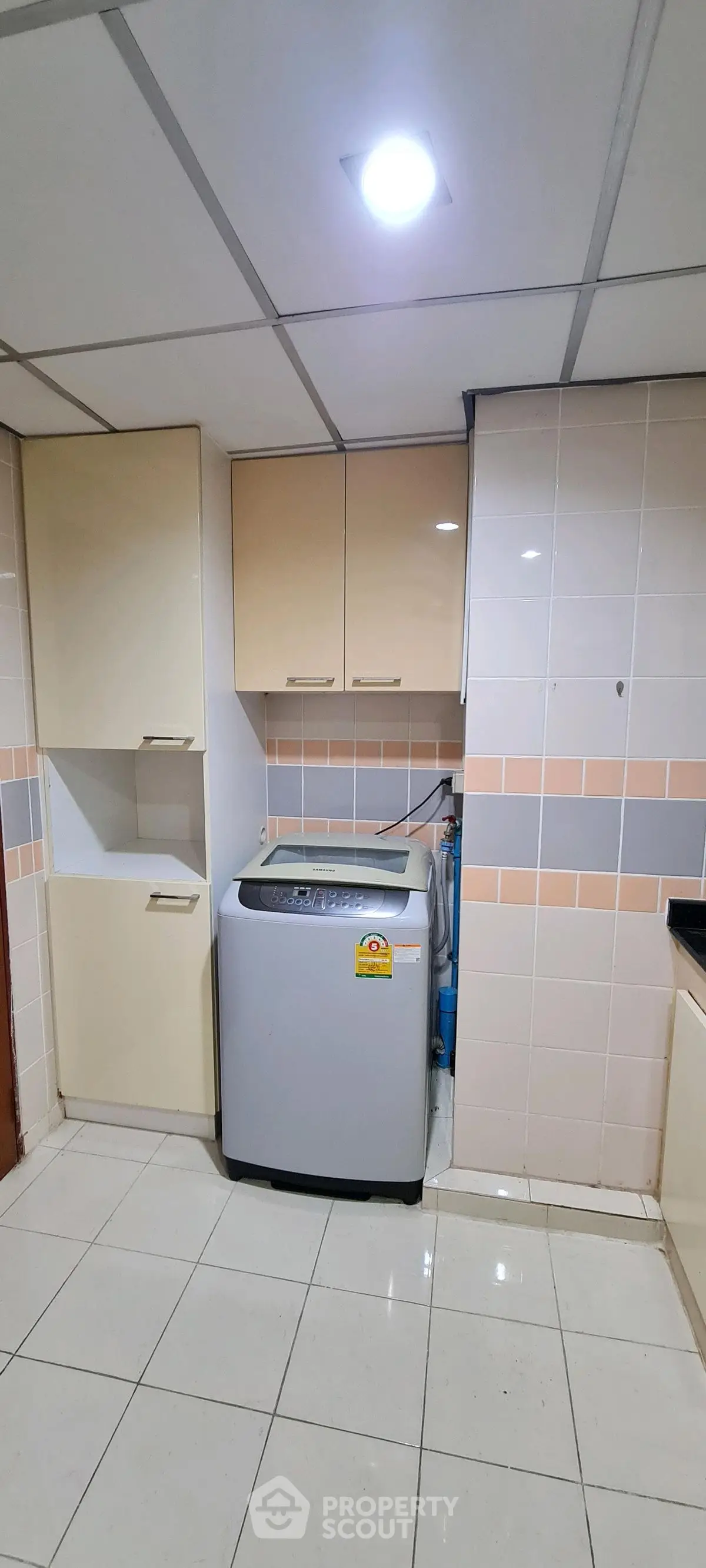 Spacious laundry area with modern washing machine and ample storage cabinets.