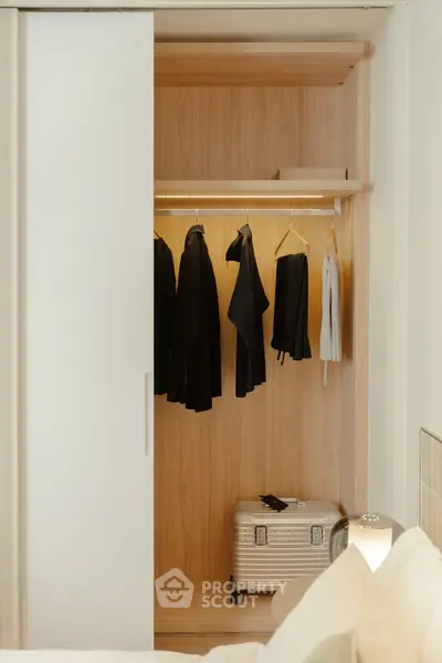 Modern bedroom with open closet featuring wooden interior and stylish clothing display.
