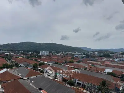 Scenic aerial view of suburban neighborhood with red-roofed houses and lush green hills.