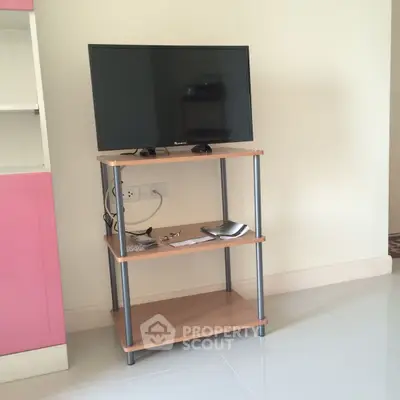 Compact living room setup with TV on wooden stand and pink cabinet
