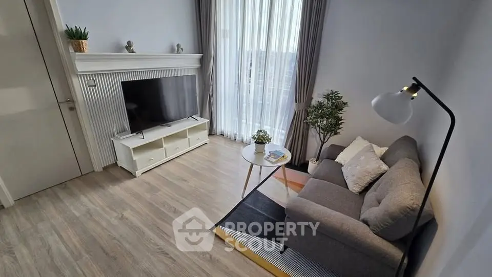 Cozy living room with modern decor, featuring a comfortable sofa, flat-screen TV, and large window for natural light.