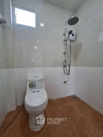 Modern bathroom with shower and toilet, featuring sleek tiles and compact design.