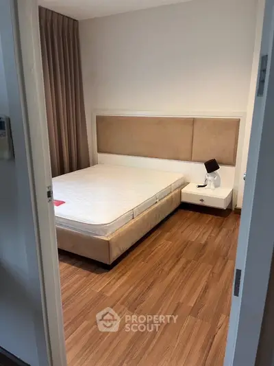 Cozy bedroom with wooden flooring and elegant headboard, perfect for restful nights.