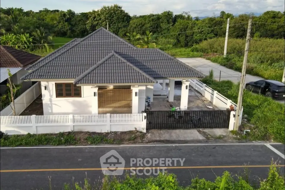Charming single-story house with modern roof and spacious driveway in lush green setting.