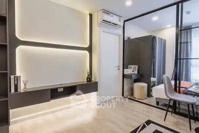 Modern living room with sleek design and ambient lighting, featuring a stylish workspace and cozy bedroom view.