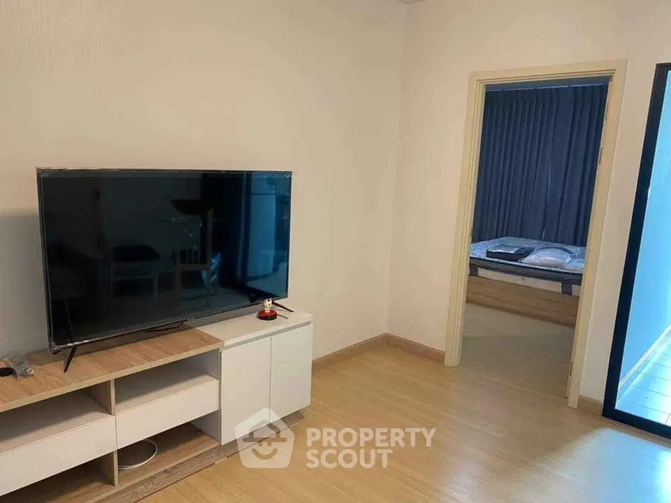 Modern living room with TV and view into cozy bedroom
