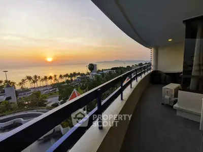Stunning sunset view from a spacious balcony overlooking the ocean and palm-lined beach.