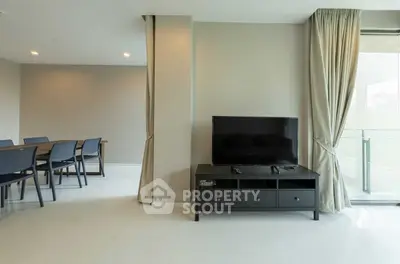 Modern living room with sleek TV stand and dining area, featuring elegant curtains and minimalist design.