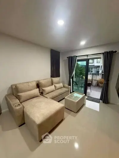 Modern living room with beige sofa and access to outdoor balcony in stylish apartment.